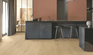 Cocina moderna con suelo vinílico adhesivo o click de madera clara, isla oscura y taburetes.