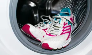 Un par de deportivas blancas con detalles fucsia y turquesa listas para lavar en lavadora.