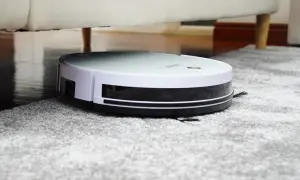 Robot aspirador Rowenta en alfombra gris, bajo un sofá. Las opiniones sobre este robot son muy positivas.