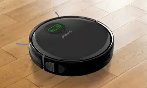 Robot aspirador negro sobre suelo de madera, listo para su reparación.