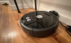 Robot aspirador negro sobre suelo de madera, parece que el roomba no detecta la base de carga.