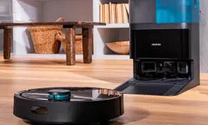 Robot aspirador negro junto a su base de carga con depósito azul.