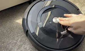 Mano presionando el botón "CLEAN" en un Roomba e5, quizás por **roomba e5 problemas**.