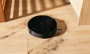 Robot aspirador Conga 999 en acción, limpiando la suciedad del suelo de madera.