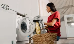 Mujer con ropa sucia junto a la lavadora, lista para poner la lavadora.