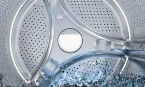Interior de lavadora con agua salpicando. Averigua cuántos litros gasta una lavadora para optimizar tu consumo.
