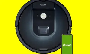 Robot aspirador Roomba 981 negro junto a un smartphone con pantalla verde.