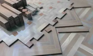 Tablas de parquet de madera apiladas y en proceso de instalación, formando un patrón de espiga. ¿Cuántas veces se puede acuchillar el parquet antes de que se desgaste?