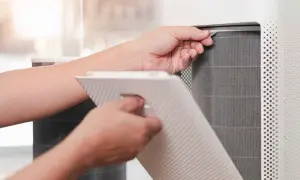Persona saca un filtro HEPA de un purificador de aire para limpiarlo.
