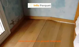 Parquet bufado en una esquina, con marcas de humedad en la pared. Se muestra cómo solucionar un parquet levantado.