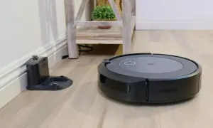Aspiradora robot negra junto a su base de carga, lista para un mapeo rápido del hogar.