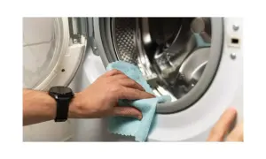Mano limpiando la goma de la lavadora para eliminar el mal olor.