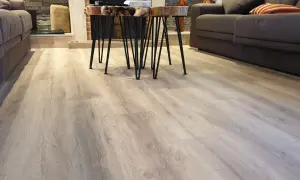 Suelo de tarima flotante de madera clara, con un diseño moderno y natural. Las medidas de la tarima flotante son perfectas para este salón.