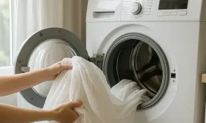 Manos colocando cortinas blancas en lavadora. Usando suavizante para un lavado fresco.
