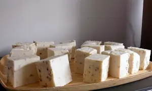 Bloques de jabón casero para lavadora, con trozos visibles de hierbas o especias, dispuestos en una bandeja de madera.