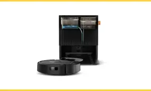 Robot aspirador negro junto a su base de carga, que incluye depósitos de agua y suciedad, creando una zona de exclusión para el polvo.