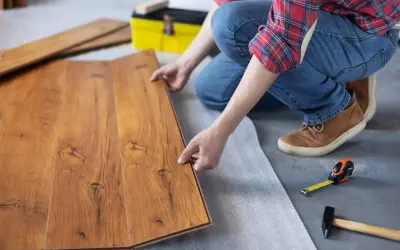 Persona instala parquet flotante de madera, colocando una tabla sobre otra.