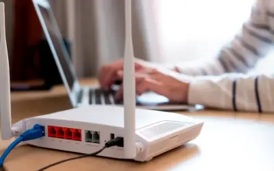 Persona frustrada intenta conectar un portátil a un router que no se enciende. Cables azules y negros conectados.