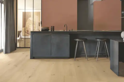 Cocina moderna con suelo vinílico adhesivo o click de madera clara, isla oscura y taburetes.