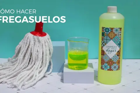 Un mocho blanco, un vaso con líquido verde brillante y una botella de limpiador para el hogar, listos para hacer un fregasuelos casero.