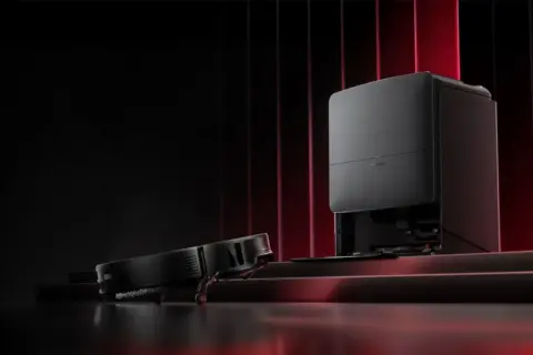 Robot aspirador negro se detiene, conga se para y no vuelve a la base. Base de carga negra con luces rojas de fondo.