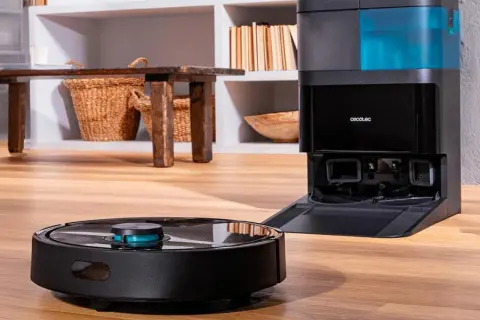 Robot aspirador negro junto a su base de carga con depósito azul.