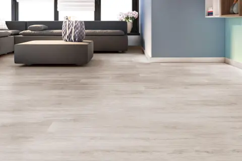 Suelos laminados colores actuales, con un sofá gris y una mesa de centro, en una sala de estar moderna.