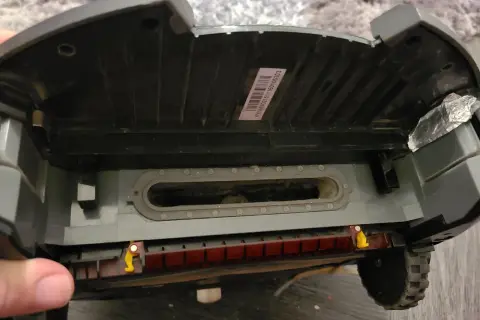 El robot aspirador Roomba muestra un error 10. Se ve el interior, con suciedad acumulada en el canal de succión y la escobilla.