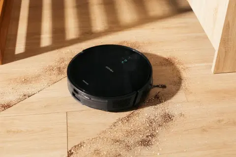 Robot aspirador Conga 999 en acción, limpiando la suciedad del suelo de madera.