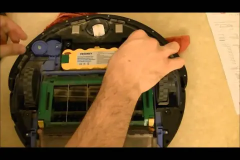 Mano arreglando un Roomba con **error 15**. Se ve la batería amarilla y las escobillas.