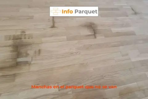 Manchas oscuras y persistentes en el parquet de madera clara, un problema común que requiere solución.