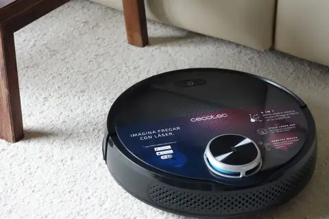 Robot aspirador Conga negro sobre alfombra blanca. Pregúntate cuanto tarda en cargar la Conga para tenerla lista para limpiar.