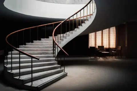 Escalera de caracol con peldaños de mármol y barandilla de madera. Diversos tipos de revestimientos para escaleras interiores.