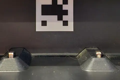 Dos contactos de carga de un Roomba, con un marcador QR encima. Posible error de carga 1.