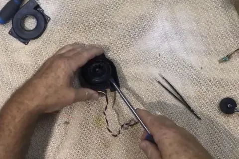 Reparando el ventilador de un Roomba con error 26. Se usa un destornillador para desmontar la pieza.