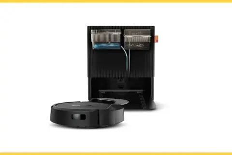 Robot aspirador negro junto a su base de carga, que incluye depósitos de agua y suciedad, creando una zona de exclusión para el polvo.