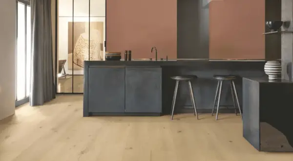 Cocina moderna con suelo vinílico adhesivo o click de madera clara, isla oscura y taburetes.