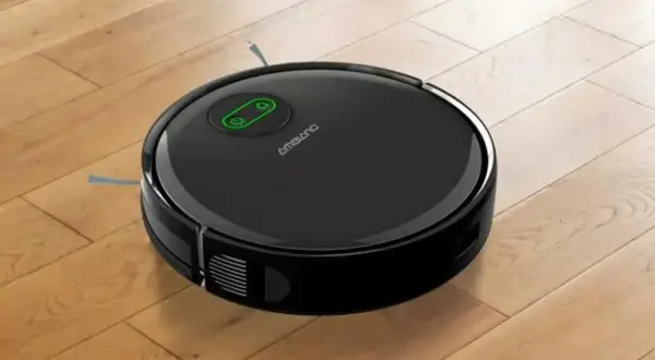 Robot aspirador negro sobre suelo de madera, listo para su reparación.