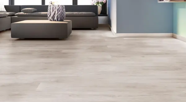 Suelos laminados colores actuales, con un sofá gris y una mesa de centro, en una sala de estar moderna.