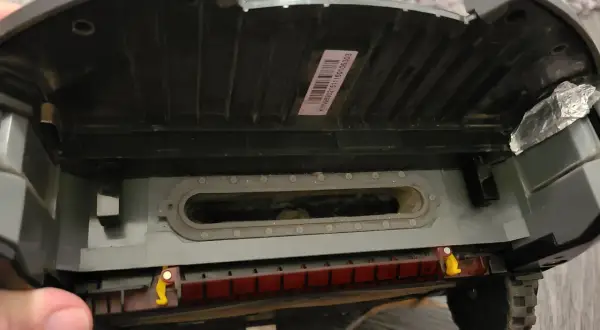 El robot aspirador Roomba muestra un error 10. Se ve el interior, con suciedad acumulada en el canal de succión y la escobilla.