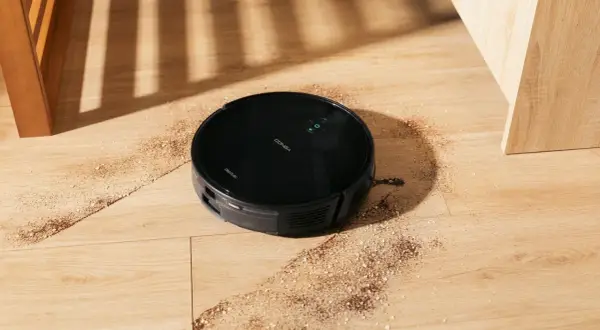 Robot aspirador Conga 999 en acción, limpiando la suciedad del suelo de madera.