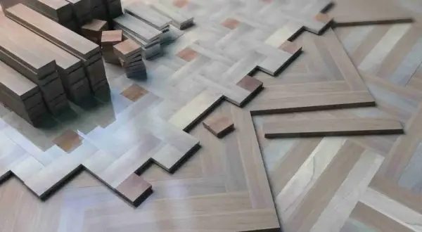Tablas de parquet de madera apiladas y en proceso de instalación, formando un patrón de espiga. ¿Cuántas veces se puede acuchillar el parquet antes de que se desgaste?