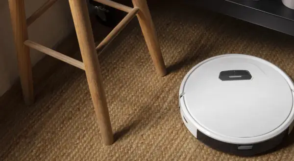 Robot aspirador Cecotec en alfombra de yute, cerca de las patas de una silla de madera. ¿Posibles averías?
