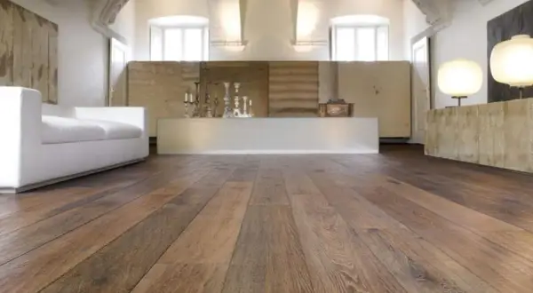 Acuchillado de parquet de madera rústica en un salón moderno con sofá blanco y lámparas.