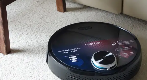 Robot aspirador Conga negro sobre alfombra blanca. Pregúntate cuanto tarda en cargar la Conga para tenerla lista para limpiar.