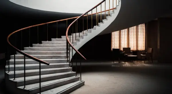 Escalera de caracol con peldaños de mármol y barandilla de madera. Diversos tipos de revestimientos para escaleras interiores.
