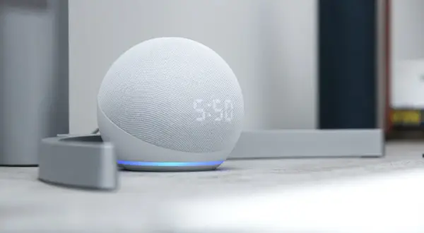 Altavoz inteligente blanco con luz azul, mostrando la hora. Descubre todo lo que puede hacer Alexa para simplificar tu día.