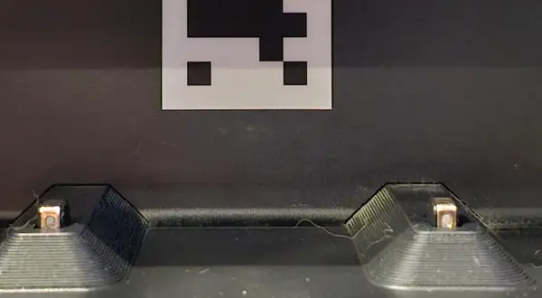 Dos contactos de carga de un Roomba, con un marcador QR encima. Posible error de carga 1.