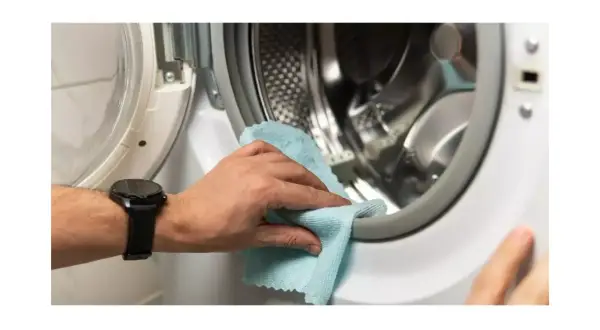 Mano limpiando la goma de la lavadora para eliminar el mal olor.