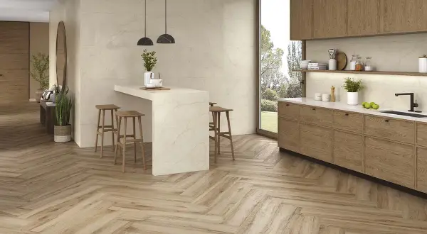 Cocina moderna con suelo de madera en espiga, el mejor suelo para cocina, isla con taburetes y muebles de madera.